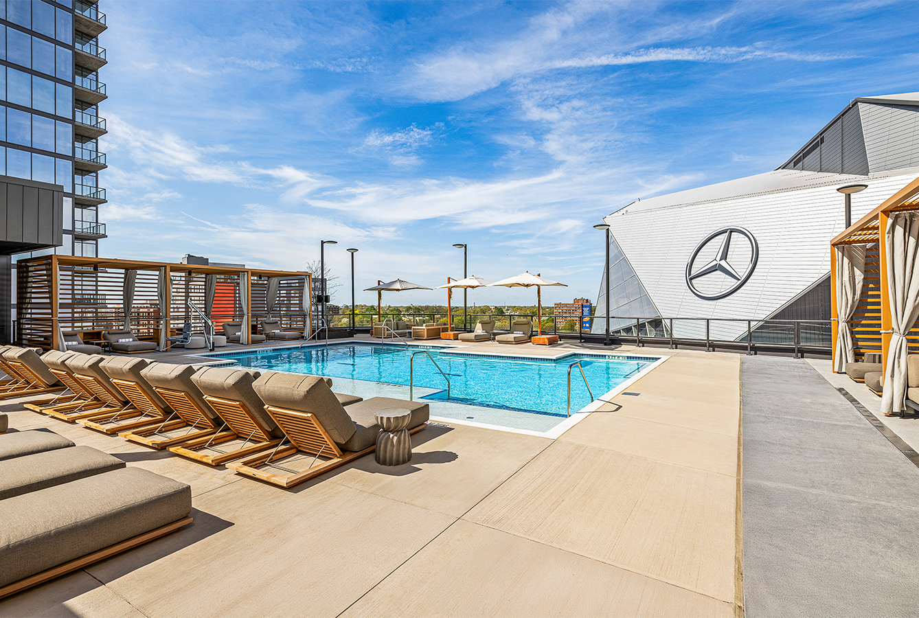a pool with lounge chairs and umbrellas on a rooftop