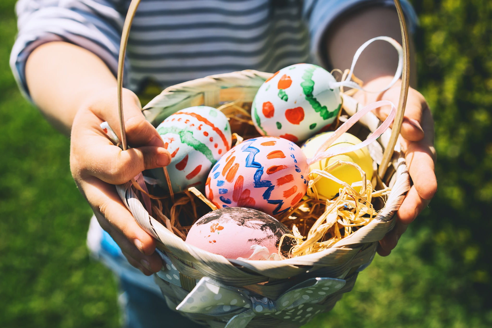 a person holding a basket of painted eggs