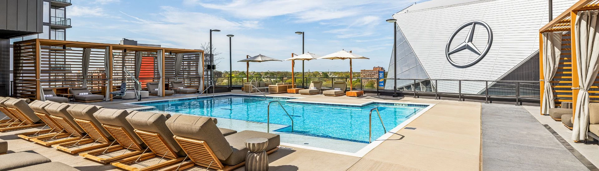 a pool with chairs and umbrellas on a rooftop
