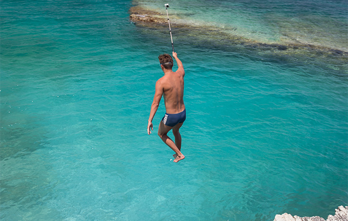 a man in swimsuits holding a stick above water
