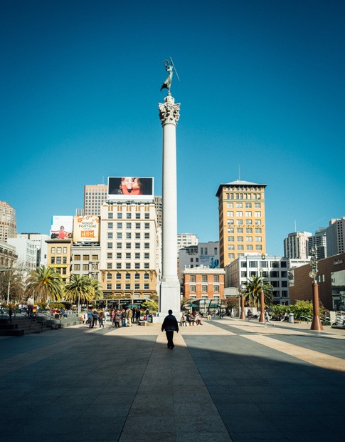Photo with a black shadow of a street and a guy walking through it at daytime