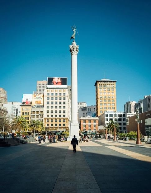 Photo with a black shadow of a street and a guy walking through it at daytime