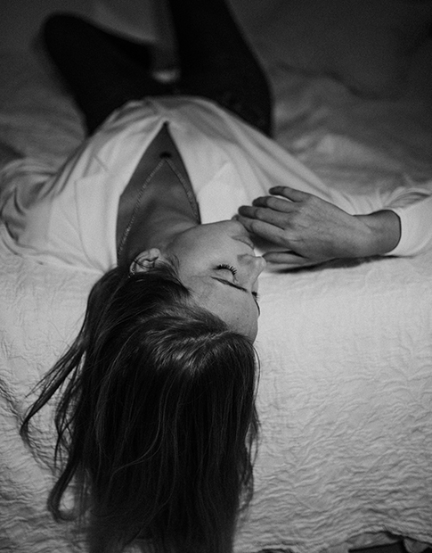 Woman laying down in the bed in a black and white photo style