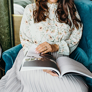 Body of married woman sitting in a blue turquoise chair while she is having a look at a book