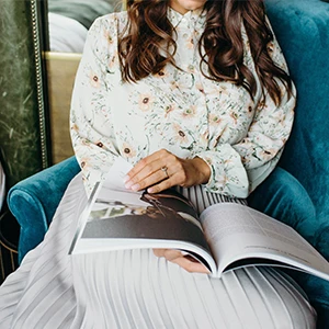 Body of married woman sitting in a blue turquoise chair while she is having a look at a book