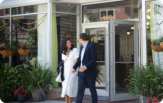 a man and woman walking in front of a glass door