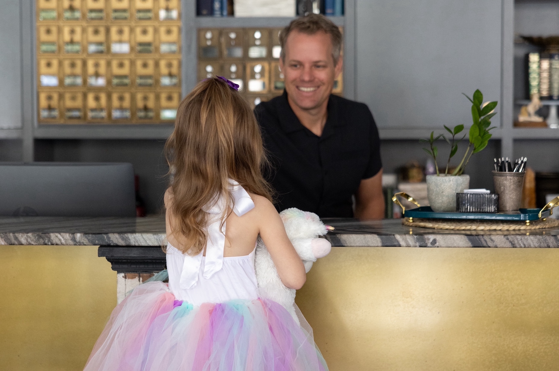 a girl sitting at a counter with a man behind her