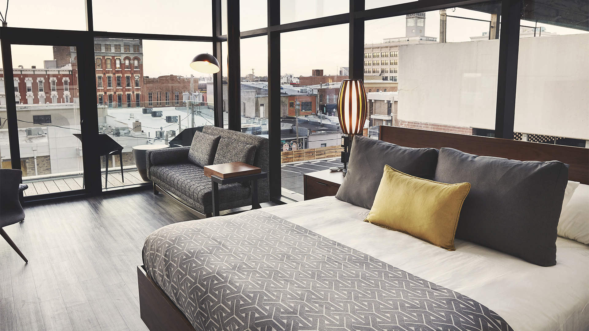 a bed with a couch and a lamp in a room with windows