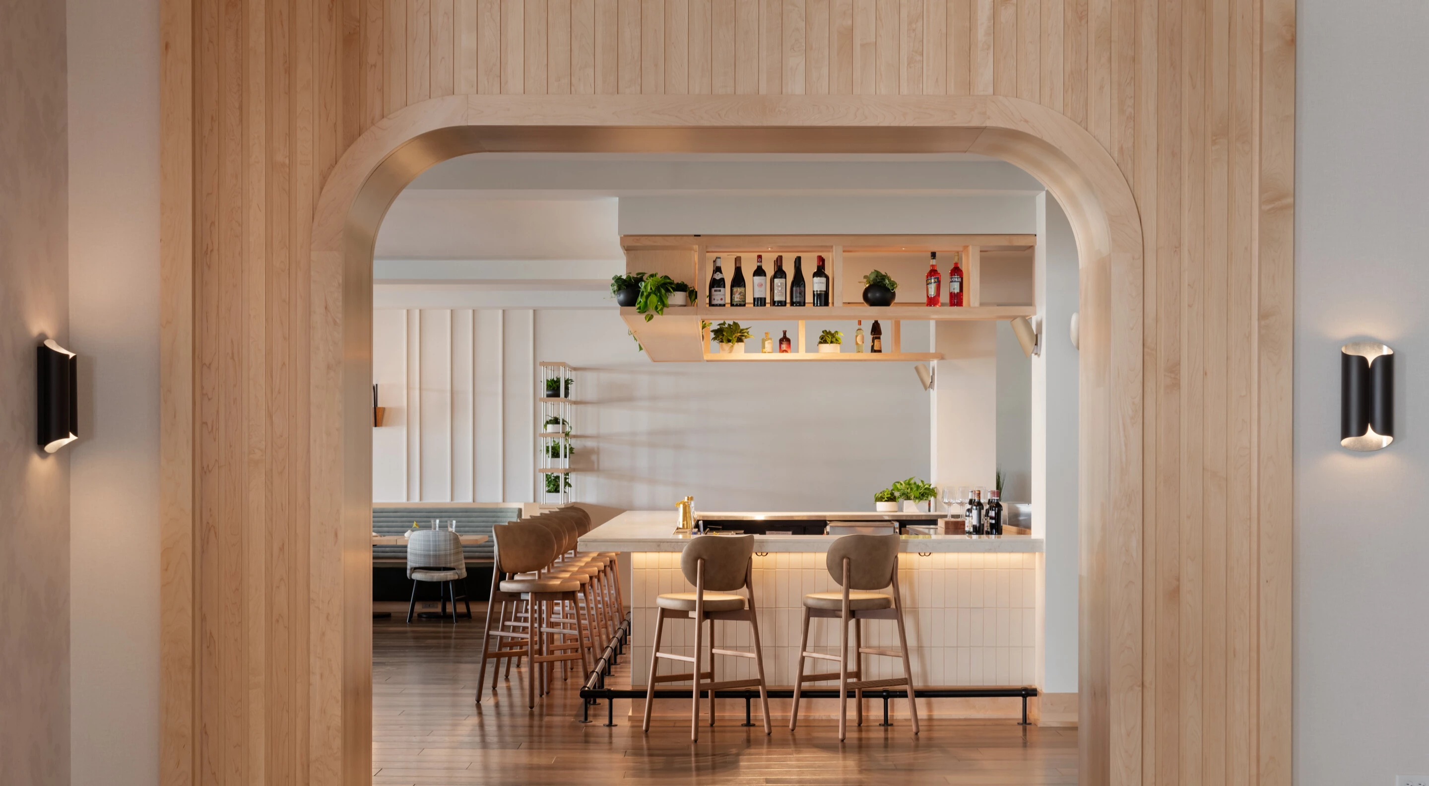 a bar with chairs and a shelf with bottles
