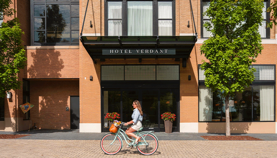 a woman riding a bicycle in front of a hotel