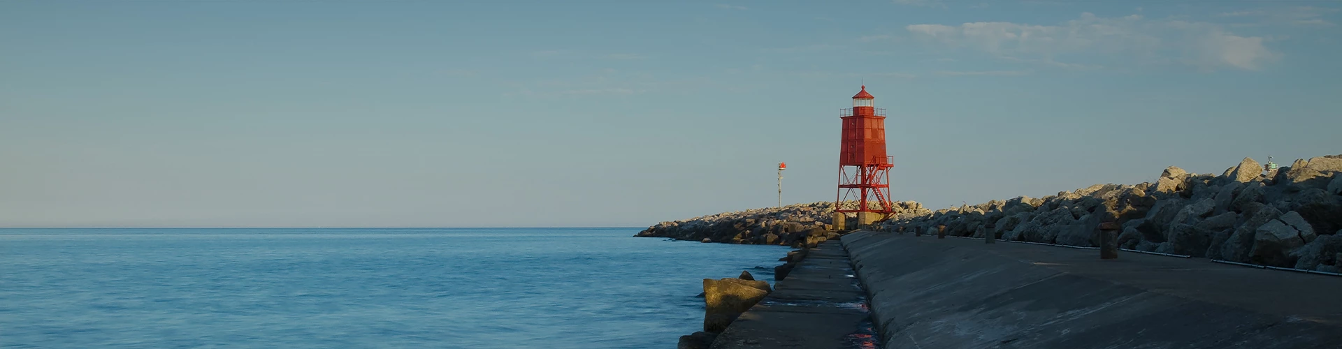 a red light house on a rocky shore