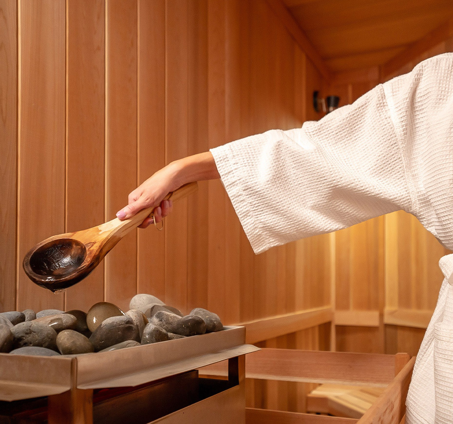 a person in a white robe holding a wooden spoon over rocks