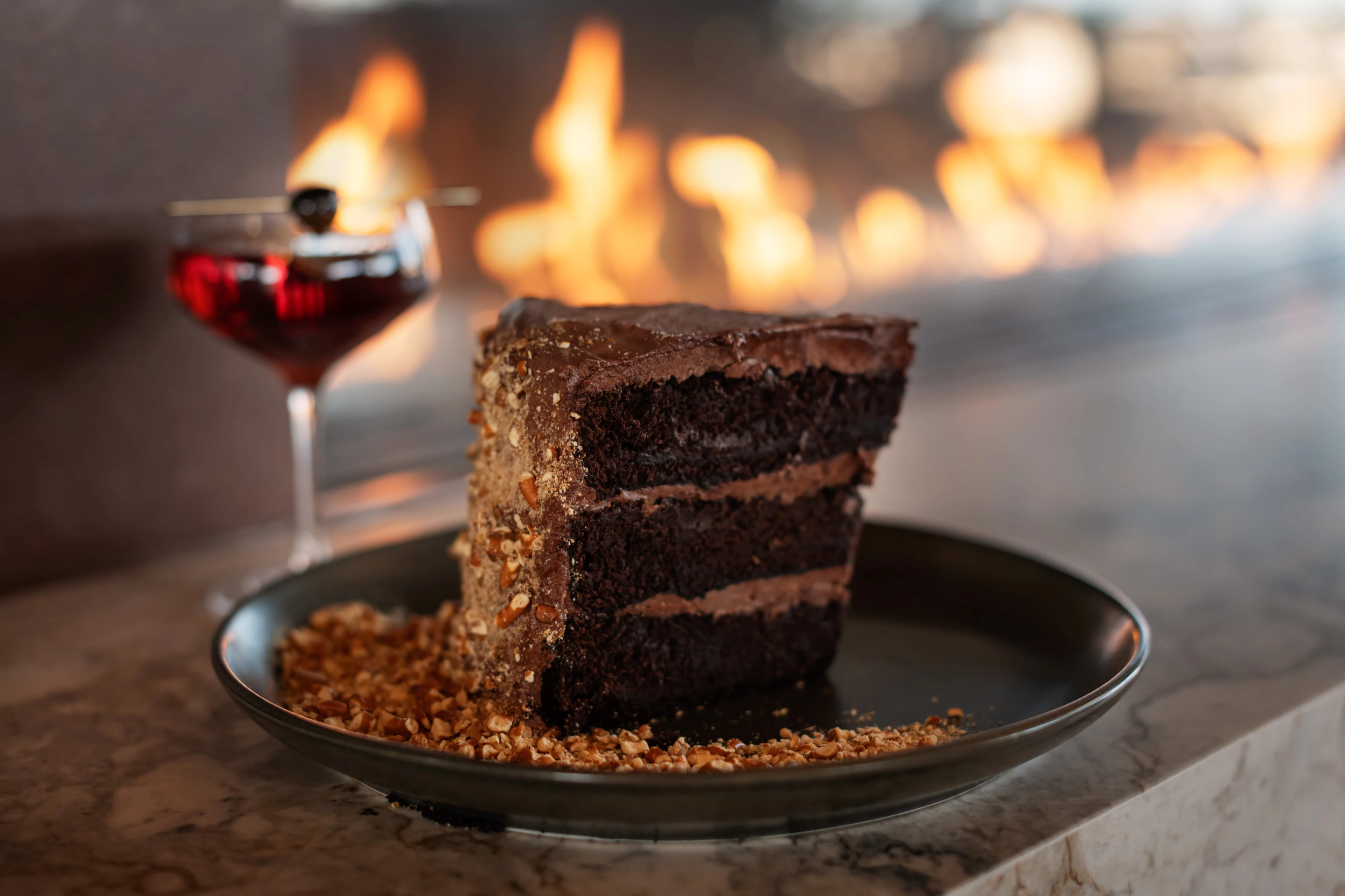 a slice of chocolate cake on a plate with a glass of wine