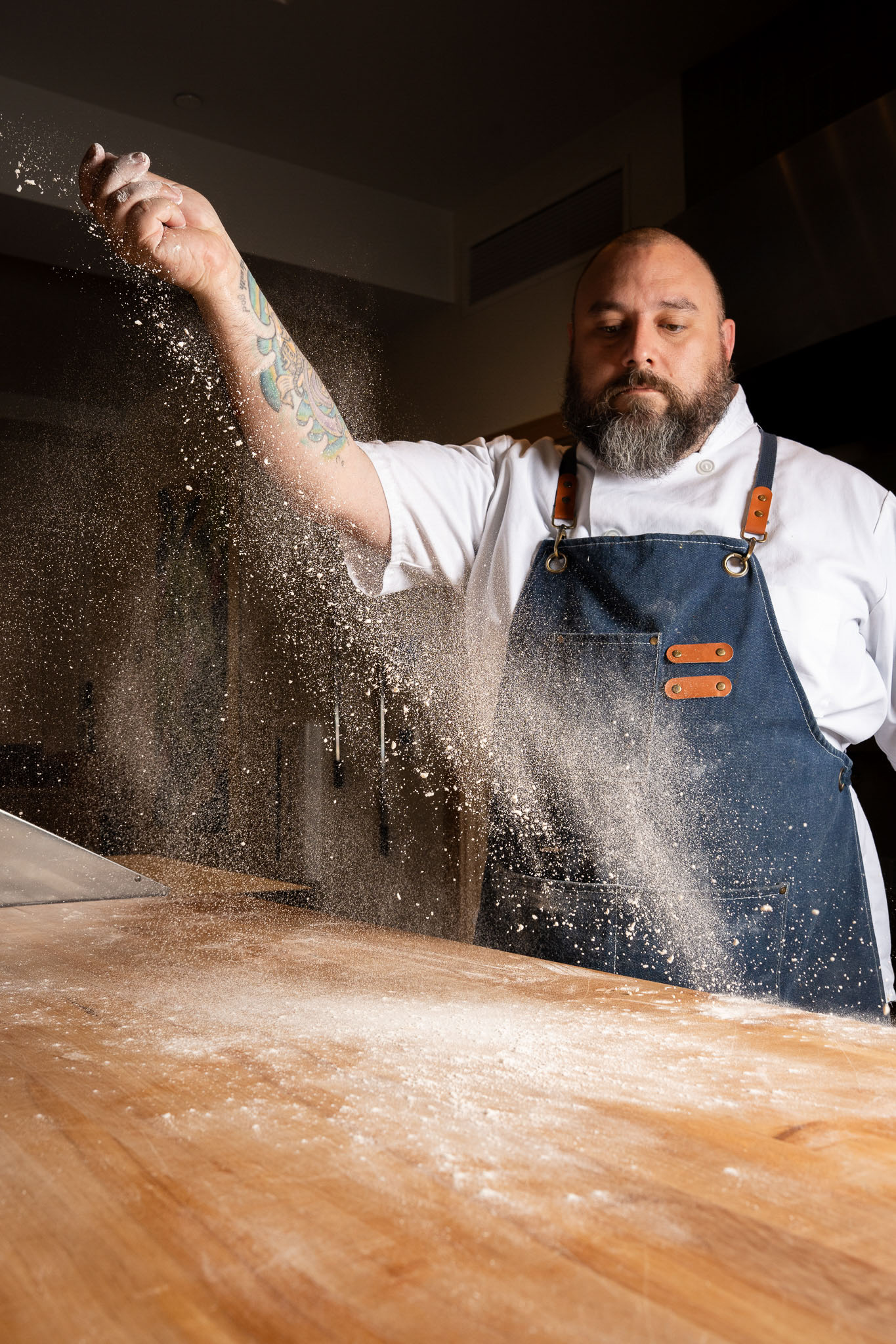a man in an apron sprinkling flour