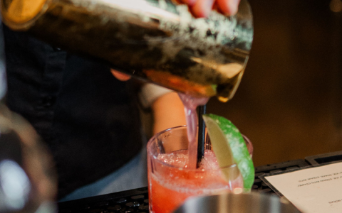 a person pouring a drink into a glass
