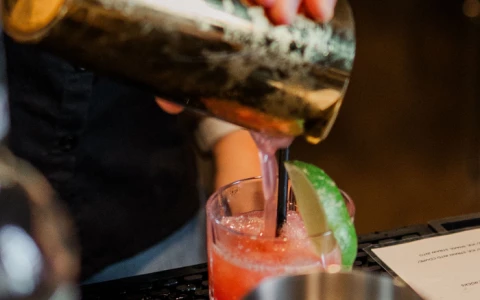 a person pouring a drink into a glass