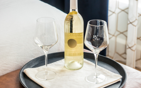 a bottle and two wine glasses on a tray
