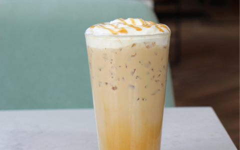 a glass of coffee with whipped cream and caramel sauce