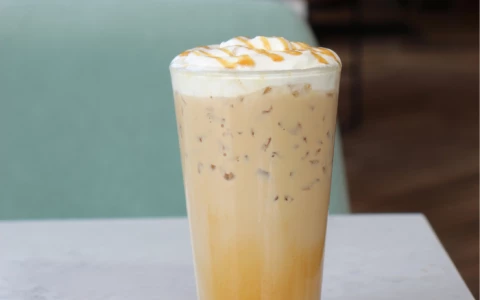 a glass of coffee with whipped cream and caramel sauce