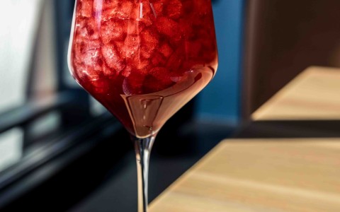 a glass of red liquid with ice and fruit