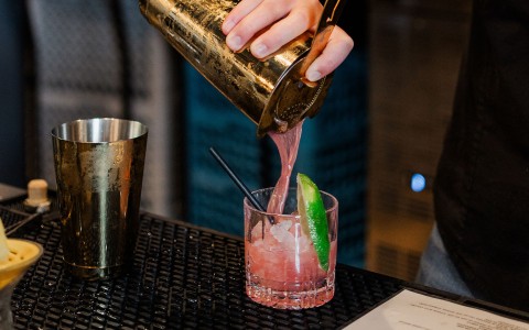 a person pouring a drink into a glass