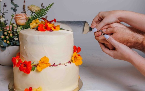 a person cutting a cake with flowers