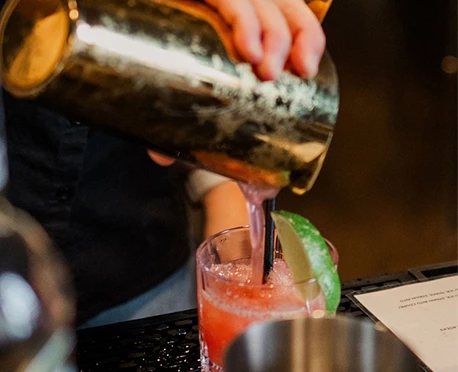 a person pouring a drink into a glass