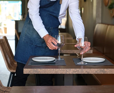 a man wearing an apron and holding wine glasses