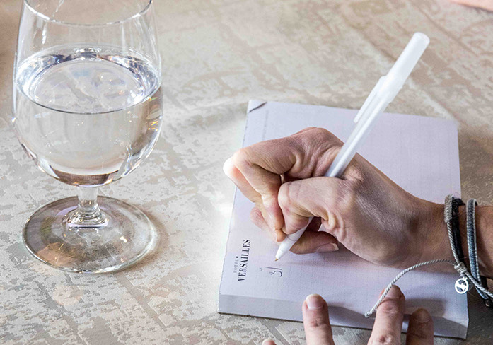 a person holding a pen and a glass of liquid
