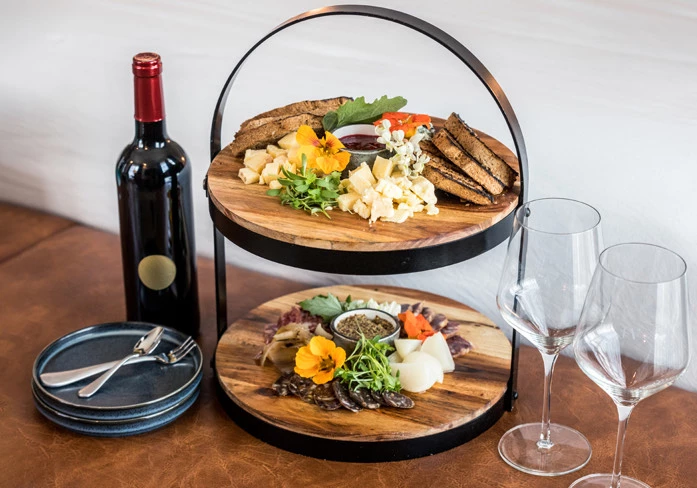 red wine bottle with two glasses of wine, small plates, and small bites