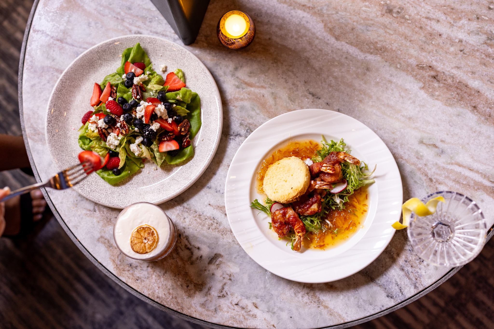 a plate of salad and a glass of lemonade on a marble table