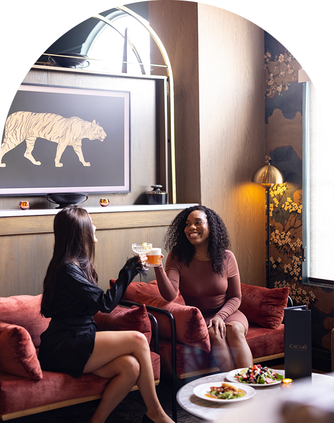 two women sitting on a couch holding drinks