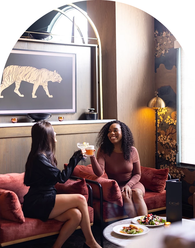 two women sitting on a couch holding drinks