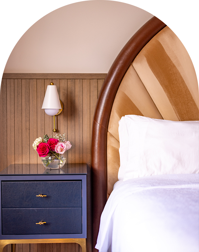 a bed with a vase of flowers on a nightstand