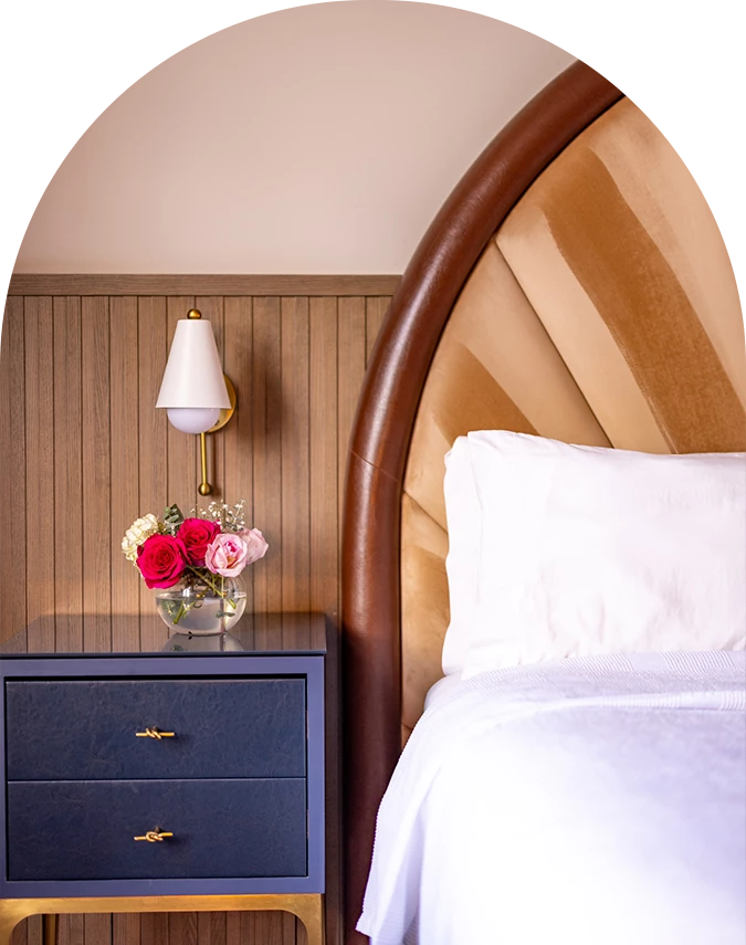 a bed with a vase of flowers on a nightstand