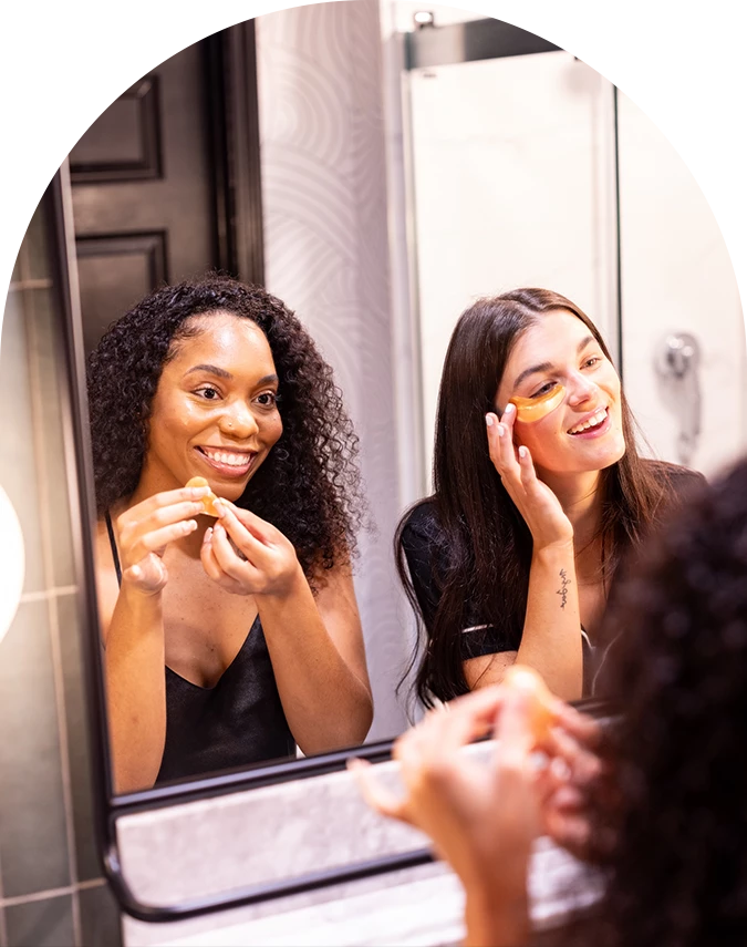 a woman smiling while holding a mask under her eyes