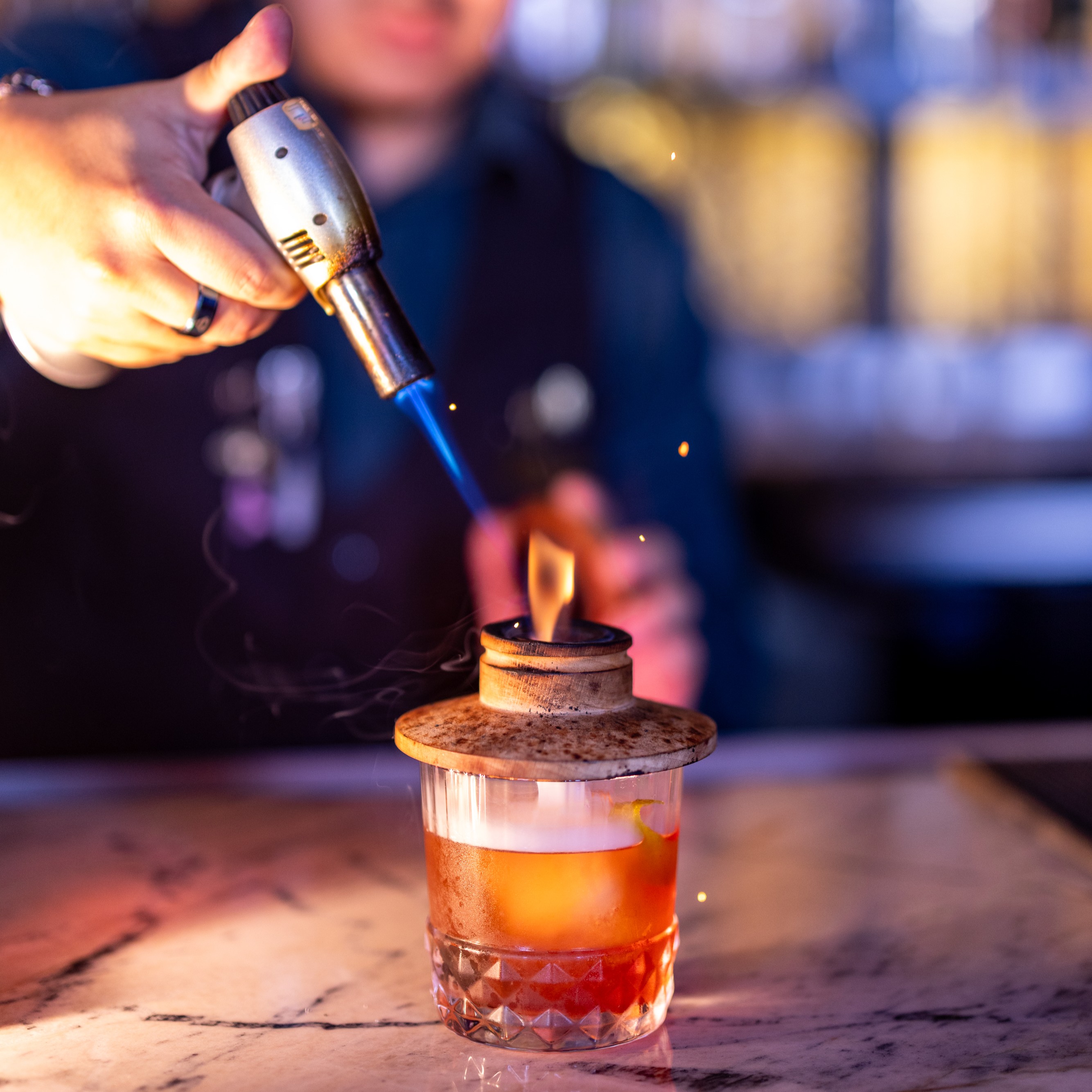 a person holding a lighter over a glass with liquid