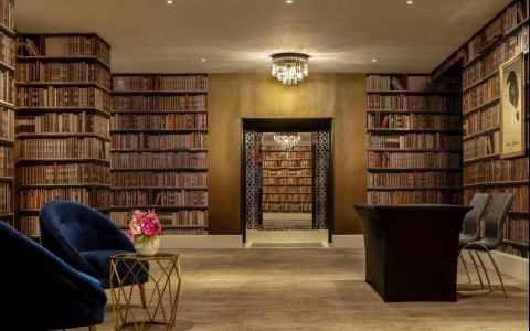 a room with a blue chair and a table with books on the shelves