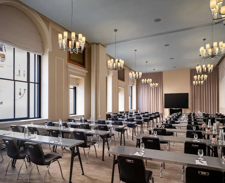 a room with tables, chairs, and a screen