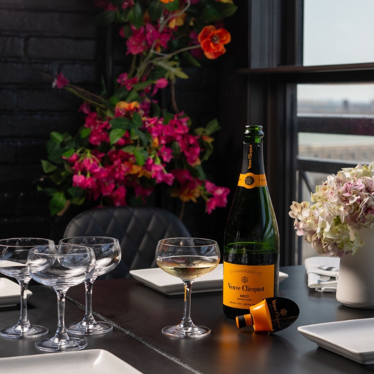 a table with four champagne glasses and an open bottle of veuve champagne