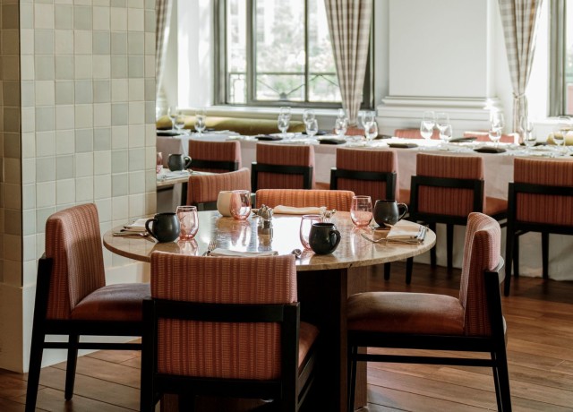 A dining area with round tables and pink chairs.