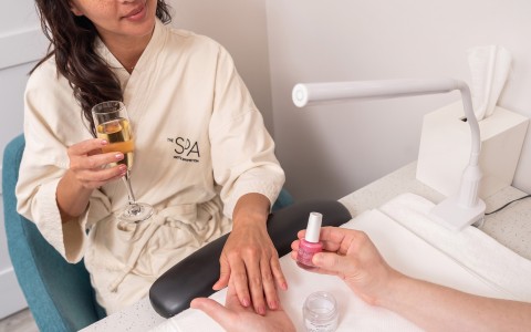 a woman holding a glass of wine and a hand with a nail polish