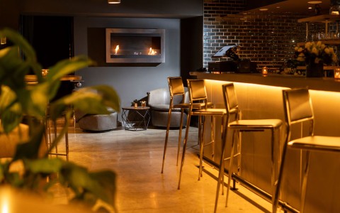a bar with chairs and a fireplace