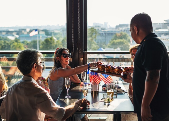 a group of people sitting at a table with food preview