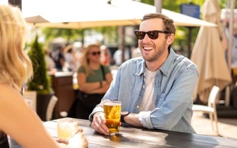 a man wearing sunglasses and holding a drink