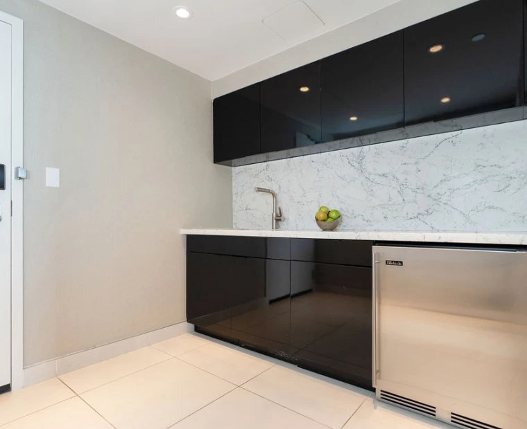 a kitchen with black cabinets and a stainless steel refrigerator