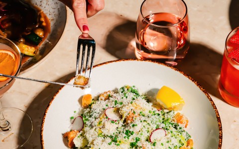 a hand holding a fork over a plate of food