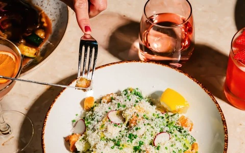 a hand holding a fork over a plate of food
