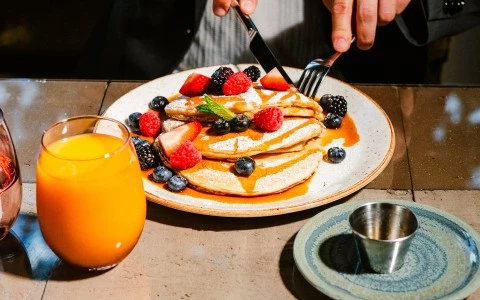 a plate of pancakes with berries and syrup