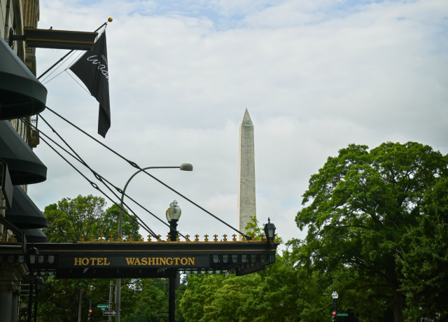 a sign with a flag and a monument in the background preview
